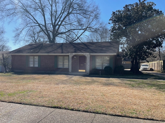 view of front of property featuring brick siding, fence, and a front yard