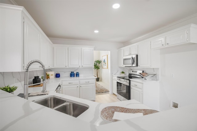 kitchen with stainless steel appliances, white cabinetry, and ornamental molding