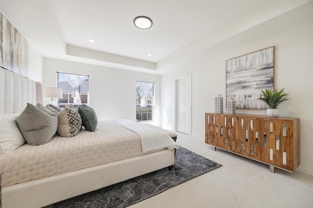 carpeted bedroom featuring baseboards, a raised ceiling, and recessed lighting