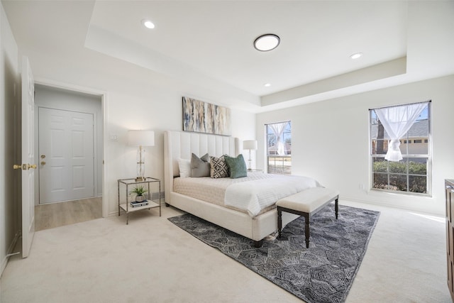 carpeted bedroom with recessed lighting, a raised ceiling, and baseboards