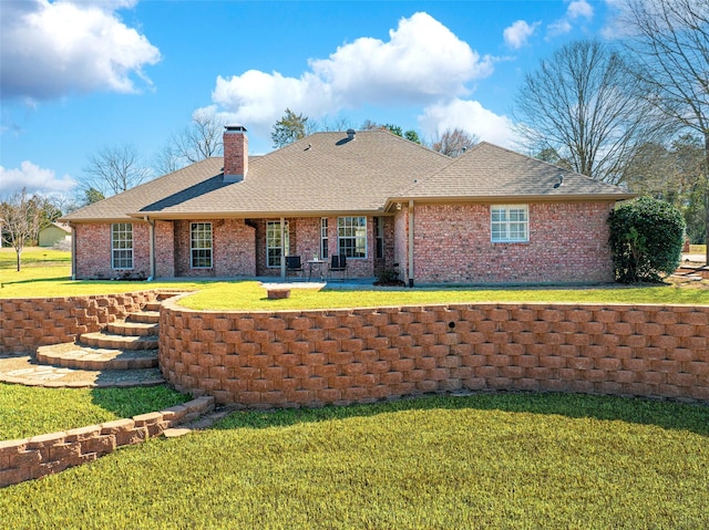 back of property featuring a shingled roof, brick siding, a lawn, and a chimney