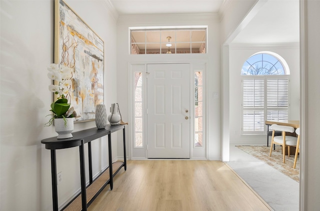 foyer with ornamental molding, a healthy amount of sunlight, and wood finished floors