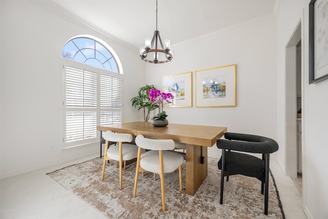 carpeted dining space with an inviting chandelier, baseboards, and ornamental molding