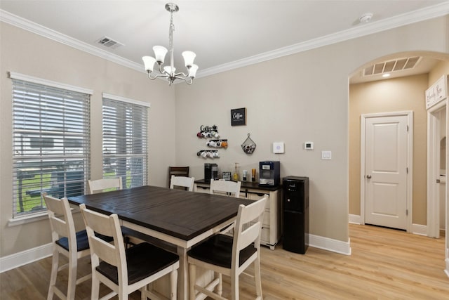 dining space with light wood-type flooring, visible vents, and arched walkways