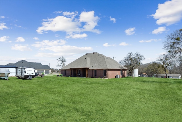 rear view of property featuring brick siding, a lawn, and central AC unit