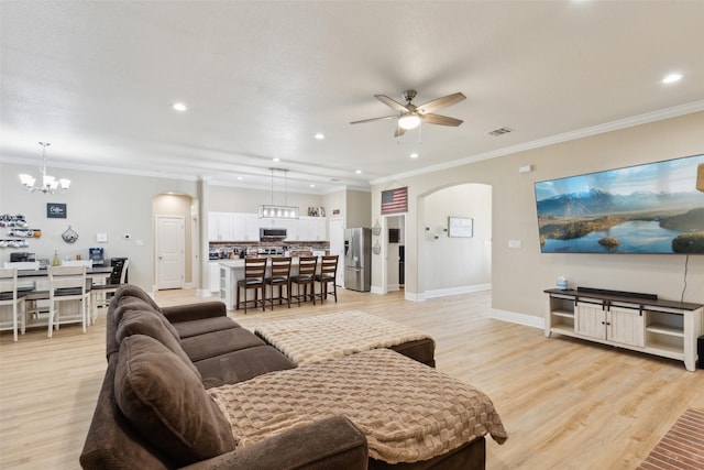 living area with arched walkways, ceiling fan with notable chandelier, baseboards, light wood-style floors, and ornamental molding