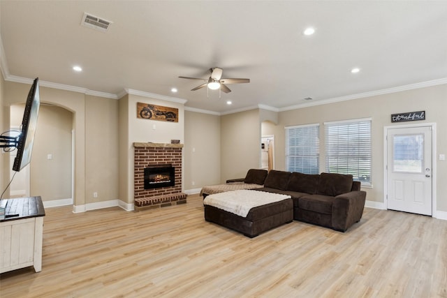 living room featuring baseboards, visible vents, wood finished floors, crown molding, and a fireplace