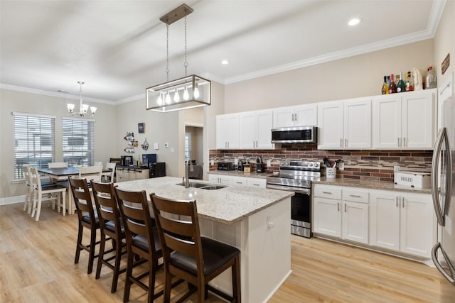 kitchen with crown molding, light wood finished floors, stainless steel appliances, white cabinetry, and a sink