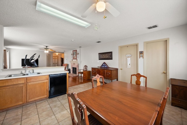 dining space featuring light tile patterned floors, a textured ceiling, a fireplace, visible vents, and a ceiling fan