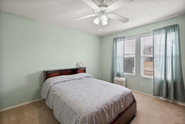 bedroom featuring ceiling fan, baseboards, a textured ceiling, and light colored carpet