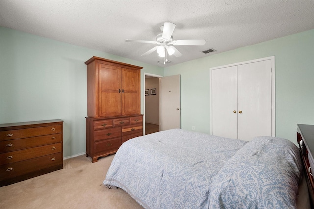 bedroom featuring a textured ceiling, light carpet, visible vents, a ceiling fan, and a closet