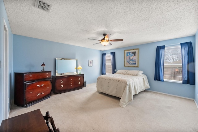 bedroom with ceiling fan, a textured ceiling, carpet flooring, and visible vents