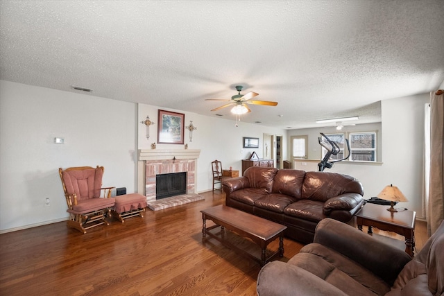 living room featuring visible vents, a ceiling fan, wood finished floors, a textured ceiling, and a fireplace