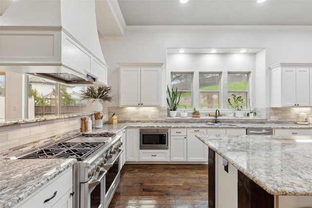 kitchen featuring dark wood finished floors, stainless steel appliances, decorative backsplash, ornamental molding, and a sink