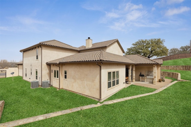 rear view of property with a tiled roof, a lawn, a chimney, and fence