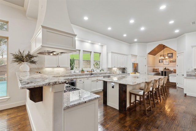 kitchen featuring white cabinetry, a kitchen breakfast bar, ornamental molding, custom exhaust hood, and tasteful backsplash