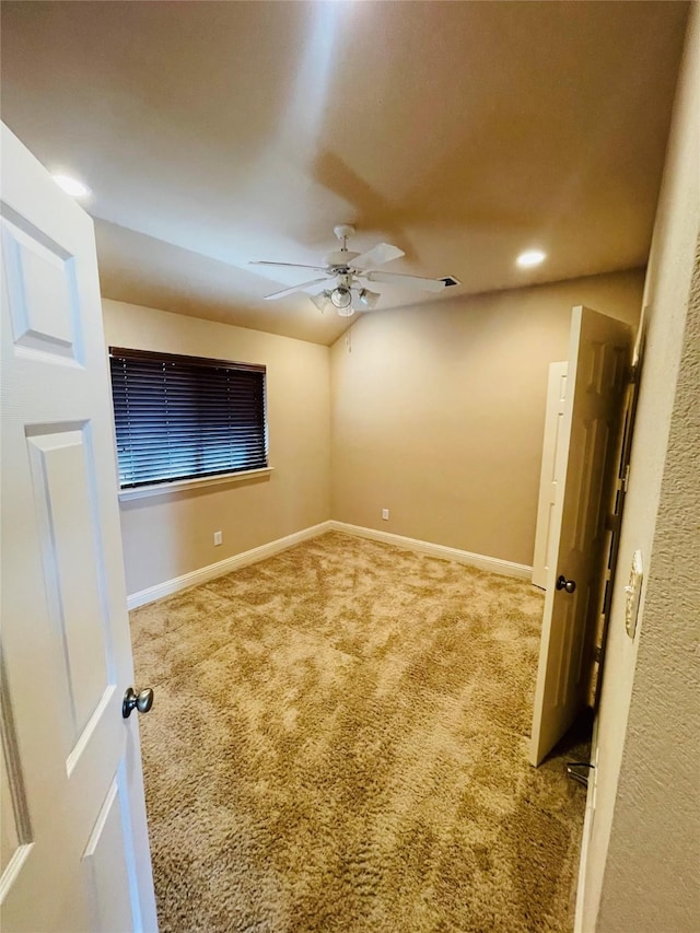 carpeted spare room featuring ceiling fan, vaulted ceiling, and baseboards