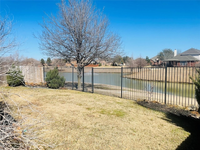 view of pool featuring a lawn, a water view, fence, and a residential view