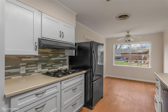 kitchen featuring ornamental molding, decorative backsplash, visible vents, and under cabinet range hood