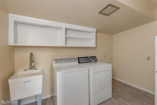 washroom featuring light wood-style floors, washing machine and dryer, a sink, laundry area, and baseboards