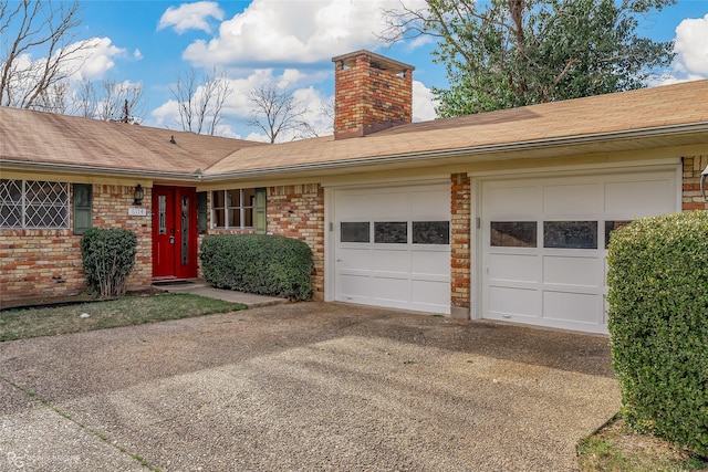 single story home with aphalt driveway, a chimney, an attached garage, and brick siding