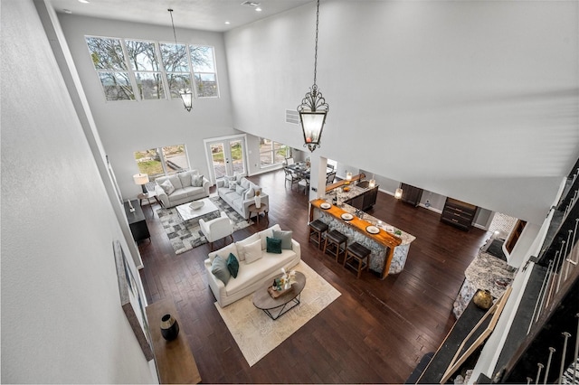 living area featuring french doors, a high ceiling, hardwood / wood-style flooring, and an inviting chandelier