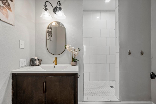 full bath with a tile shower and vanity