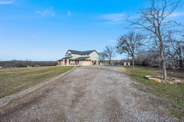 view of front facade featuring a garage, a front lawn, and dirt driveway