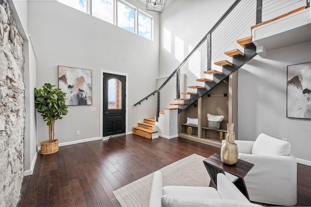 foyer entrance featuring stairway, wood finished floors, a towering ceiling, and baseboards