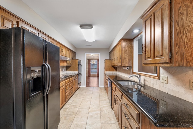 kitchen featuring a sink, baseboards, black appliances, tasteful backsplash, and brown cabinetry