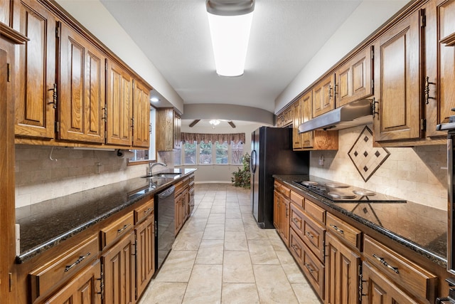 kitchen featuring black appliances, under cabinet range hood, brown cabinets, and a sink