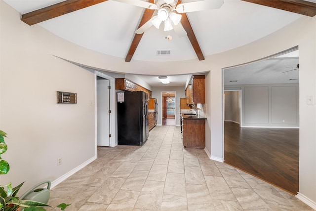 kitchen with visible vents, baseboards, black fridge with ice dispenser, ceiling fan, and vaulted ceiling with beams