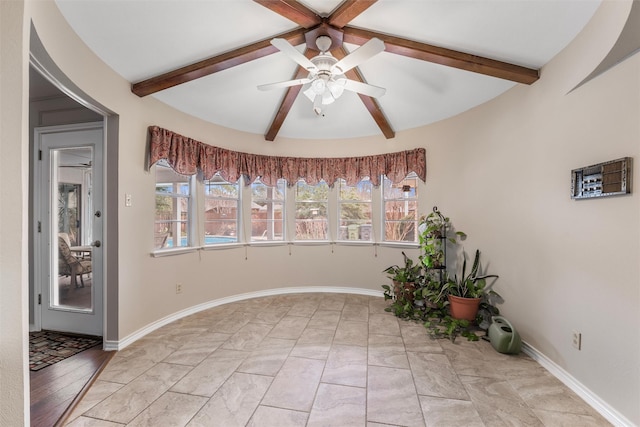 empty room featuring ceiling fan, lofted ceiling with beams, and baseboards