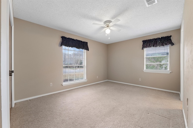 carpeted spare room with ceiling fan, a textured ceiling, visible vents, and baseboards