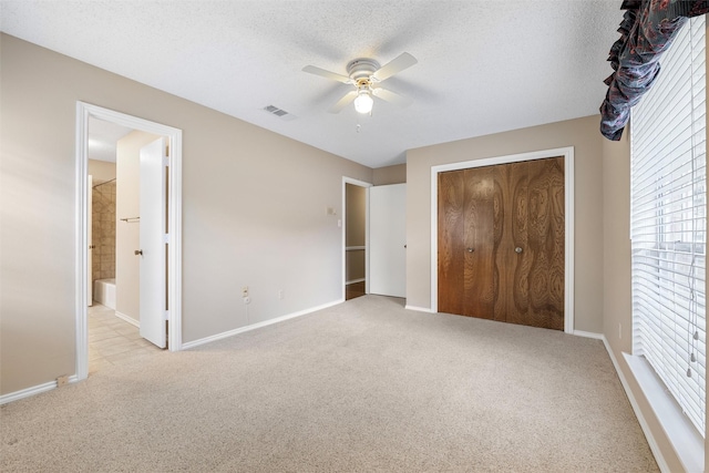 unfurnished bedroom featuring a closet, light colored carpet, a textured ceiling, and baseboards