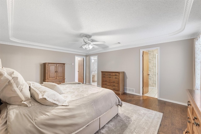 bedroom with a textured ceiling, dark wood-type flooring, visible vents, ornamental molding, and ensuite bath