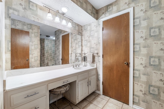 bathroom with a textured ceiling, vanity, baseboards, tile patterned floors, and wallpapered walls