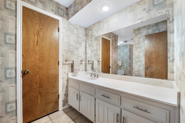 bathroom with wallpapered walls, vanity, a textured ceiling, and tile patterned floors