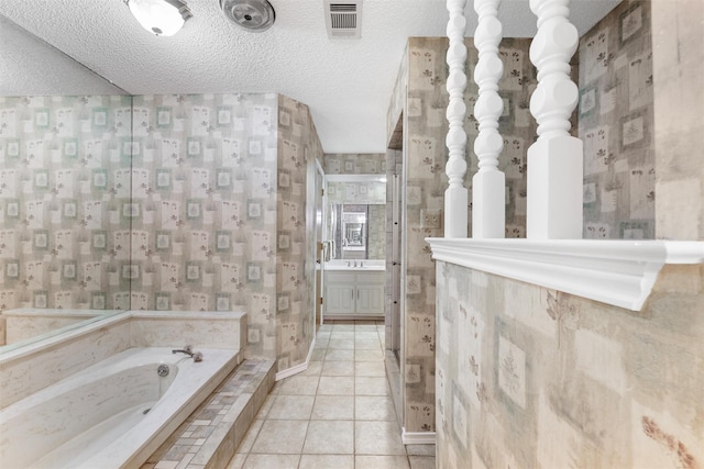 bathroom featuring a textured ceiling, a bath, and wallpapered walls