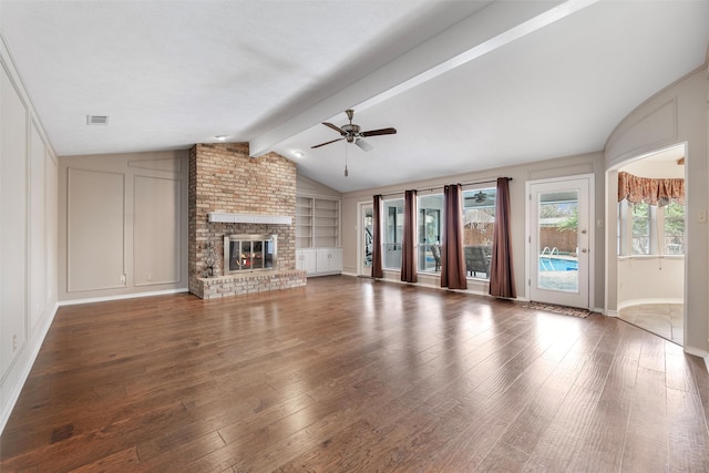 unfurnished living room with lofted ceiling with beams, a fireplace, visible vents, and a decorative wall