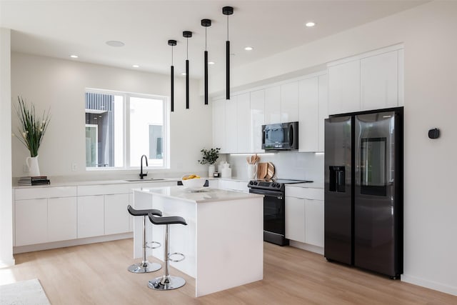 kitchen featuring light wood finished floors, electric range, a kitchen island, fridge with ice dispenser, and modern cabinets