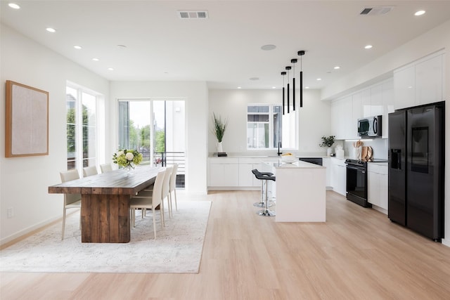 kitchen with a center island, light wood-style floors, visible vents, and black appliances