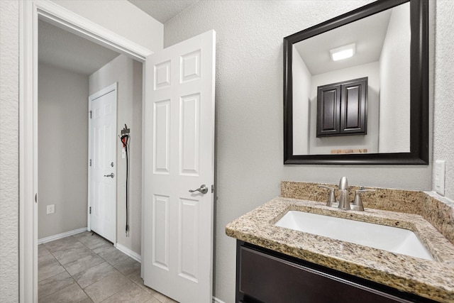 bathroom with vanity, baseboards, and tile patterned floors