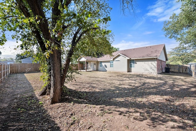 rear view of house with a fenced backyard, brick siding, and central AC unit