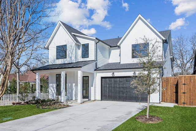 modern farmhouse style home featuring board and batten siding, a standing seam roof, covered porch, and fence