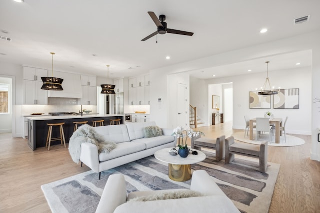 living area featuring visible vents, a ceiling fan, light wood finished floors, recessed lighting, and stairs