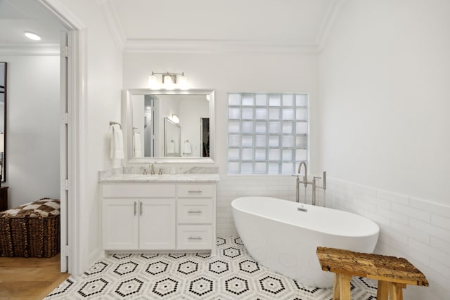 bathroom featuring a freestanding bath, tile walls, crown molding, and vanity