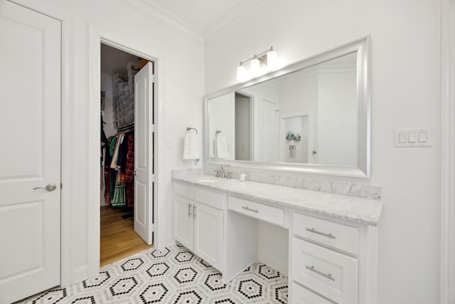 bathroom featuring a spacious closet, wood finished floors, vanity, and crown molding