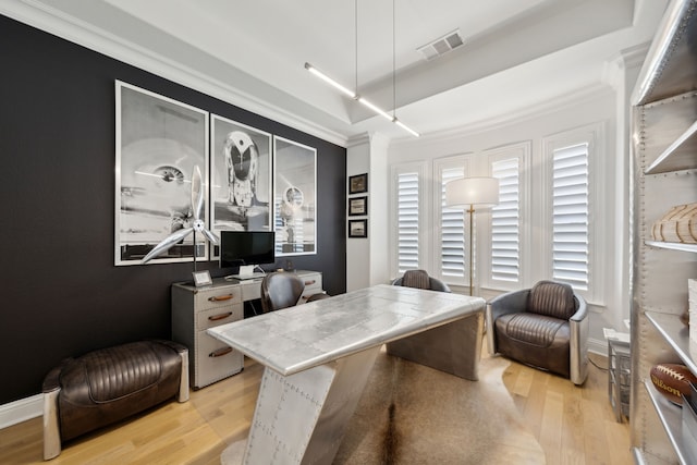 office space featuring baseboards, visible vents, a raised ceiling, crown molding, and light wood-style floors