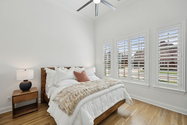 bedroom featuring ceiling fan, crown molding, baseboards, and wood finished floors